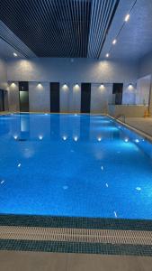 une grande piscine avec de l'eau bleue dans un immeuble dans l'établissement Ugam revers Apartments, à Khumson