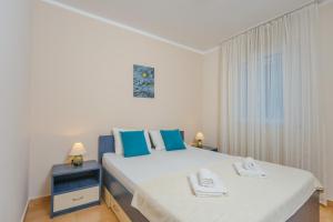 a bedroom with a large white bed with blue pillows at Apartments Spin in Budva