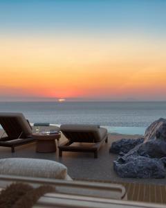 ein Sonnenuntergang über dem Meer mit zwei Stühlen und einem Tisch in der Unterkunft The Revery - Luxury Suites & Tented Pavilions, Elafonisi - Adults Friendly in Livadia