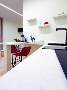 a kitchen with a white counter and red chairs at La Chicca di Ameli in San Severo