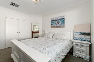 a white bedroom with a bed and a night stand at White Sands in Lancelin