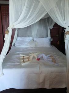 Deux personnes sont allongées sur un lit blanc dans l'établissement Pousada & Hostel Interligado Tiririca, à Itacaré