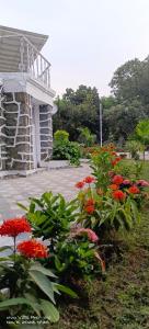 ein Garten mit roten Blumen vor einem Gebäude in der Unterkunft Chavan White House Farm and Stay in Badlapur + 14 Fotos