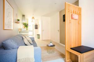 a living room with a blue couch in a room at Idéal PRO & Couple - 2 Logements Thème Boho Chic RDC & Dandy 1er étage - Quartier Calme - Jardin - WIFI HD - Smart TV - Parking Gratuit - Proche Centre & Transports - Ask Home in Valenciennes