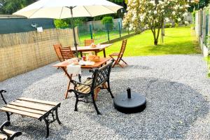 a patio with a table and chairs and an umbrella at Idéal PRO & Couple - 2 Logements Thème Boho Chic RDC & Dandy 1er étage - Quartier Calme - Jardin - WIFI HD - Smart TV - Parking Gratuit - Proche Centre & Transports - Ask Home in Valenciennes