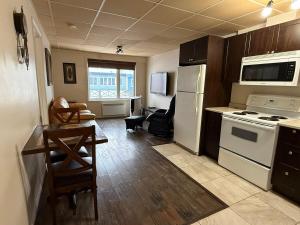 a kitchen with white appliances and a table and chairs at Apartment #2 avec chambre Baie Comeau in Baie-Comeau