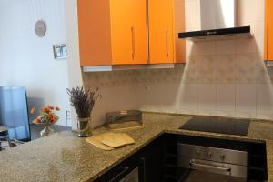 eine Küche mit orangefarbenen Schränken und einer Arbeitsplatte in der Unterkunft Alojamento Bem-me-quer in Reguengos de Monsaraz
