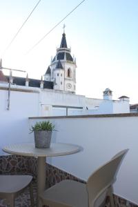 einen Tisch und Stühle auf einem Balkon mit einem Uhrturm in der Unterkunft Alojamento Bem-me-quer in Reguengos de Monsaraz