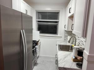 eine Küche mit einem Edelstahlkühlschrank und weißen Schränken in der Unterkunft Delmar Loop 2-Bedroom Retreat in University City