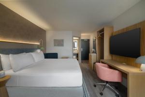 ein Hotelzimmer mit einem Bett, einem Schreibtisch und einem Fernseher in der Unterkunft EVEN Hotel Detroit North - Troy by IHG in Troy