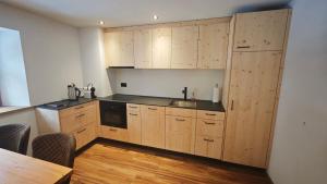 a kitchen with wooden cabinets and a wooden table at Chasa Salnuun Ferienwohnungen in Samnaun
