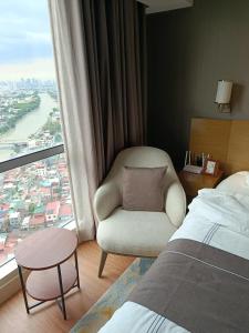 ein Schlafzimmer mit einem Stuhl, einem Bett und einem Fenster in der Unterkunft RBR Lux at Novotel Manila Hotel Residences Acqua in Manila