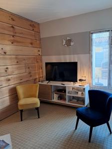 ein Wohnzimmer mit einem TV und 2 Stühlen in der Unterkunft Maisons de vacances 6 pers proche plan d'eau in L'Aiguillon-la-Presqu'île