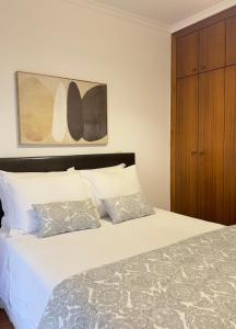 a bedroom with a white bed with a wooden cabinet at BARRAMARES 3 in Furadouro +29 photos