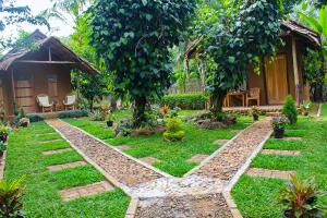 a garden in front of a house with two trees at Almond Breeze Cottage in Udawalawe