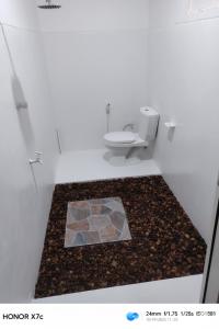 een badkamer met een toilet en een tegelvloer bij Almond Breeze Cottage in Udawalawe