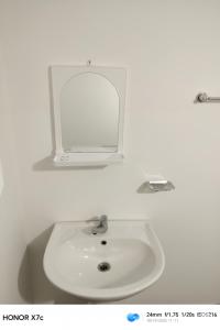 een witte wastafel in een witte badkamer met een spiegel bij Almond Breeze Cottage in Udawalawe