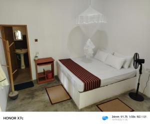 een slaapkamer met een wit bed en een houten tafel bij Almond Breeze Cottage in Udawalawe