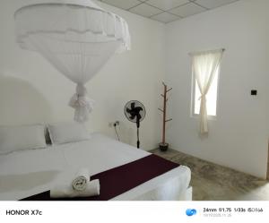 een witte slaapkamer met een groot wit bed en een raam bij Almond Breeze Cottage in Udawalawe