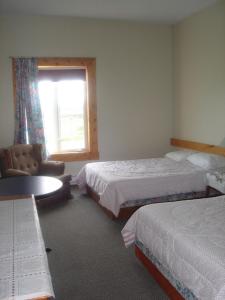 a hotel room with two beds and a chair and a window at Wildberry North in St. Anthony
