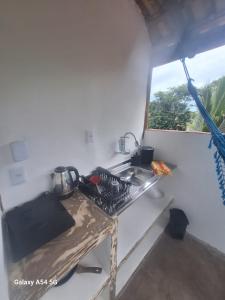 een kleine keuken met een wastafel en een raam bij Alma Surf House in Boicucanga