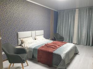 a bedroom with a bed and two chairs at Видові апартаменти на пляжі in Cherkasy