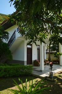 a white house with a porch and a staircase at Hideaway Lodge in Tangalle