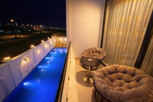 ein Balkon mit zwei Stühlen und einem Pool auf einem Gebäude in der Unterkunft H99 Homestay 