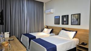 a hotel room with two beds and a desk at Granja Brasil puc 10 2 in Petrópolis +17 photos