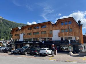 a large building with cars parked in a parking lot at Monolocale Collini in Madonna di Campiglio