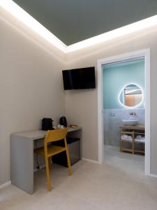 een kamer met een bureau, een wastafel en een tafel bij Cozy Rooms in Senorbì