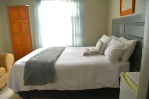 a bedroom with a large white bed with a window at Rural Villa Guesthouse in Naledi +6 photos