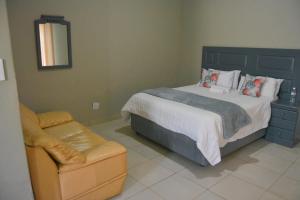 a bedroom with a large bed and a chair at Rural Villa Guesthouse in Naledi