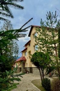 亚列姆切Гуцульська оселя的一座大黄色房子前面有树木