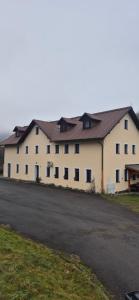 a large white building with a black roof at Krkonošský apartmán DELUXE in Poniklá