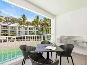 Un comedor con mesa y sillas y un balcón. en Peppers Beach Club, en Port Douglas