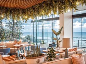 Un restaurante con mesas y sillas y vista al mar. en Peppers Soul Surfers Paradise, en Gold Coast