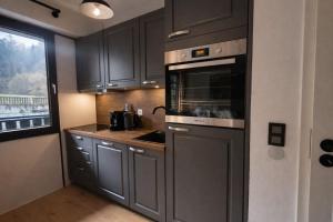 a kitchen with black cabinets and a stove top oven at 21 Gramm Das Verborgene mit Tiefgarage in Sasbachwalden