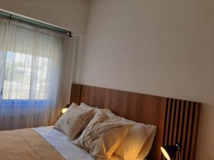 a bedroom with a bed with a wooden headboard and a window at Noche Serena in Puerto Madryn