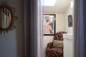 a room with a chair with a mirror and a picture at la chaume st martin in Angoulême