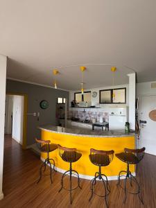 a yellow bar in a kitchen with stools at Apartamento Inteiro Próximo ao Centro in Águas de Lindoia