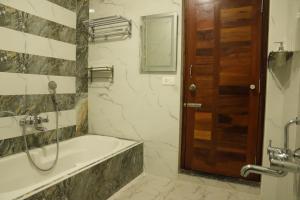 a bathroom with a bath tub and a wooden door at SK Grand Palace in Pondicherry +27 photos
