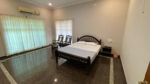 een slaapkamer met een bed en 2 stoelen. bij Abida Mansion 4BHK Near MCP Convention Centre IJK in Irinjālakuda