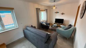 a living room with a couch and chairs and a tv at O Refúgio do Moedinhas in Peniche
