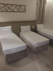 deux lits côte à côte dans une pièce dans l'établissement فندق الرسالةالذهبي شارع ام القري, à Aş Şafā