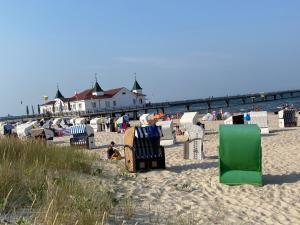 un groupe de chaises de jardin sur une plage avec une jetée dans l'établissement Ferienwohnung am Waldesrand, à Ahlbeck