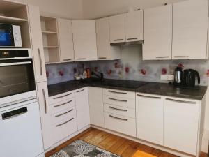 a white kitchen with white cabinets and a microwave at Jõe House in Valga
