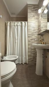 ein Badezimmer mit einem weißen Duschvorhang, einem WC und einem Waschbecken in der Unterkunft Gran Hotel Mar del Plata in Mar del Plata