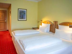 two beds in a hotel room with white sheets at Atomis Hotel Munich Airport by Mercure in Oberding