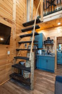 a spiral staircase in a log cabin kitchen with blue cabinets at Tiny Loft-Spider Lake-SUP Rentals-Beach-10mi to TC in Traverse City